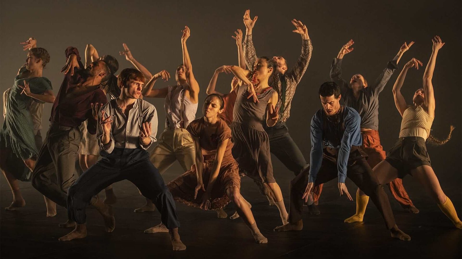 Groupe de danseurs du film En corps de Cédric Klapisch (2022) en pleine chorégraphie contemporaine sur scène, exprimant des émotions intenses à travers des mouvements expressifs dans une lumière tamisée.