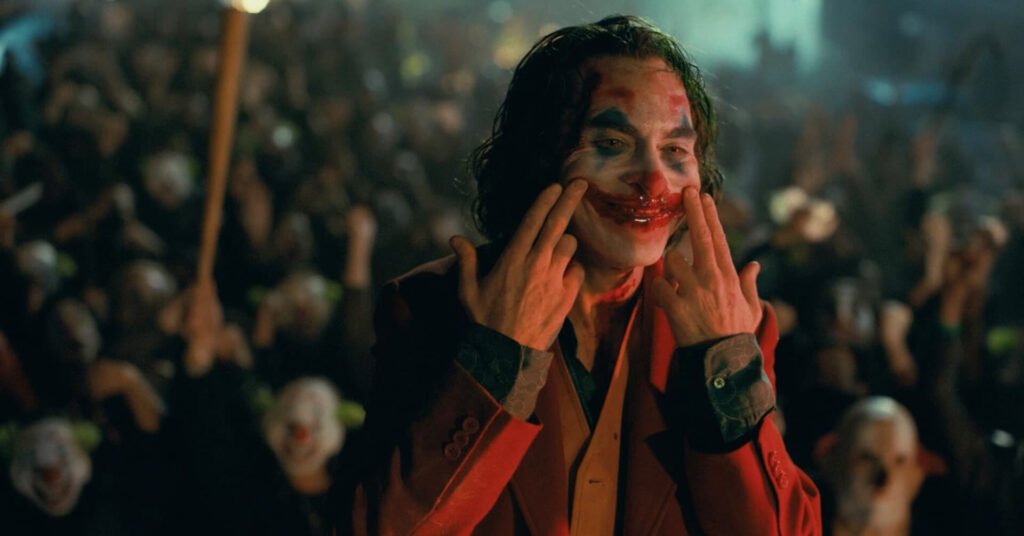 Joaquin Pheonix interprétant le Joker, faisant une grimace en sang dans la scène final du film "Joker" (2019) de Todd Phillips.